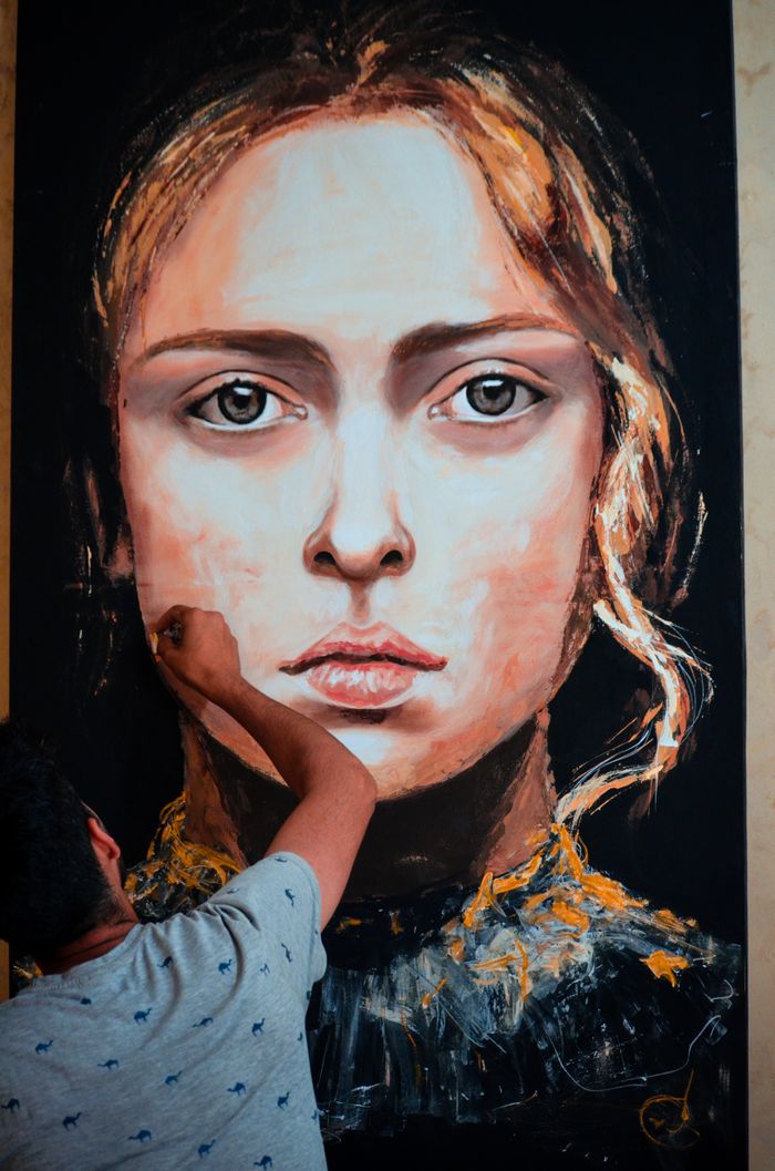 Crafting Captivating Headlines: Your awesome post title goes here An artist meticulously paints a large portrait of a woman on canvas in an indoor art studio.